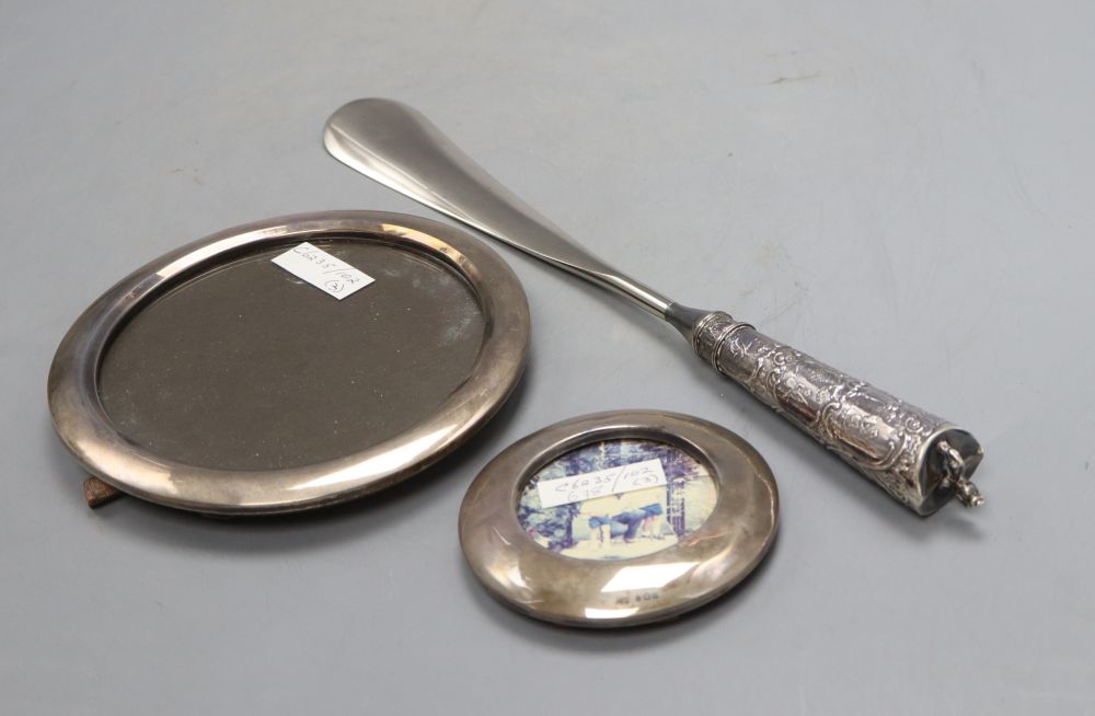Two circular silver mounted photograph frames, largest 16.4cm and a white metal handled shoe horn.